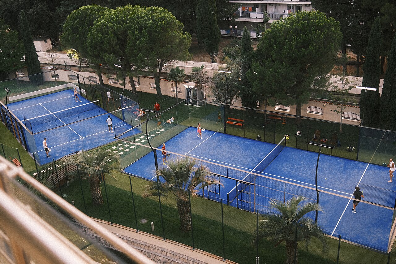 Group of padel players in a lively match on blue courts